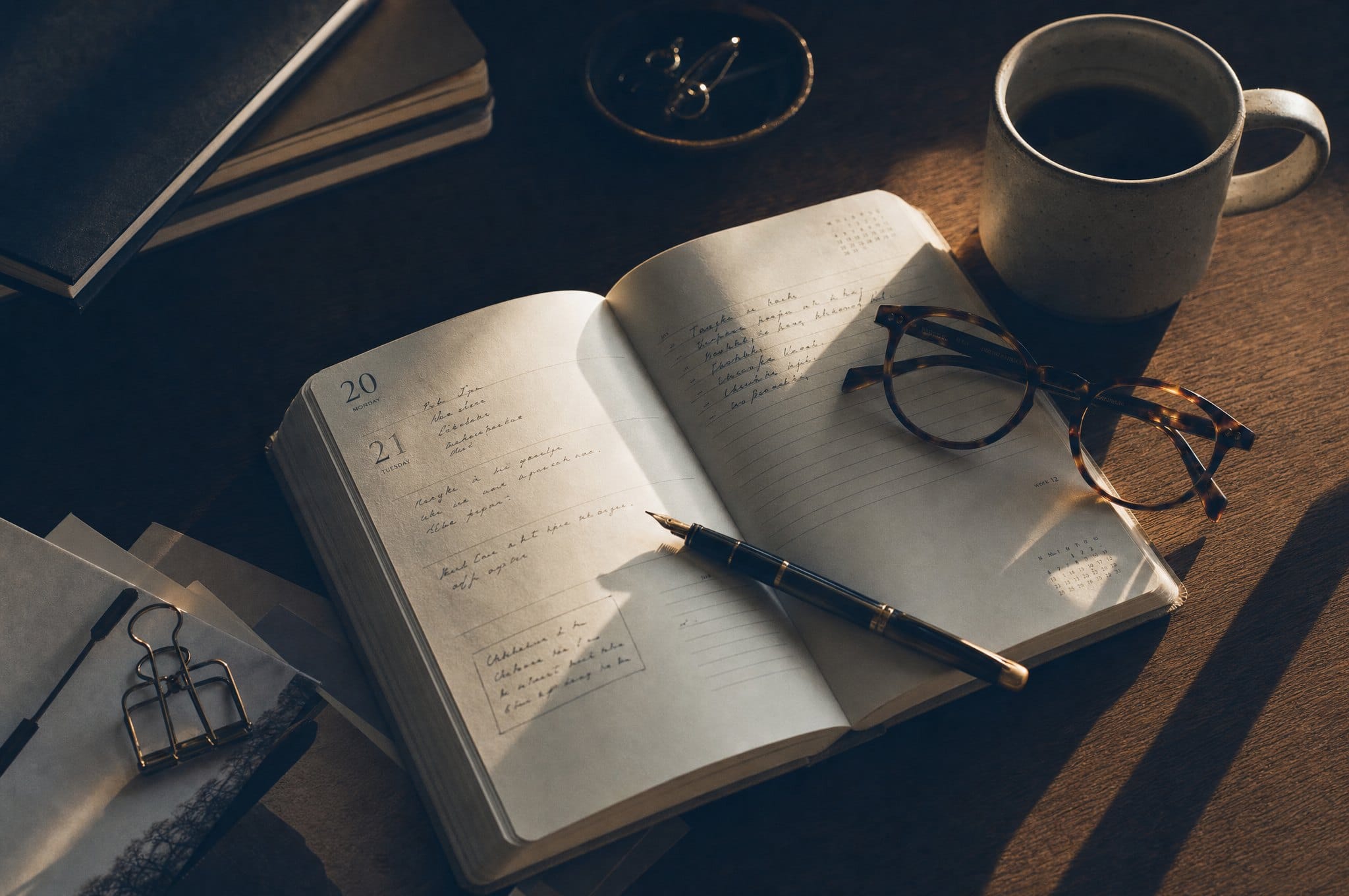 Agenda papier ouvert avec stylo plume et lunettes, préparation des échéances